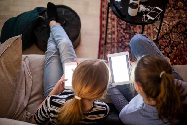 High angle view of sisters using wireless technologies while sitting on sofa at home Sweden, Stockholm, model released, property released Copyright: xMaskotx , MA80363