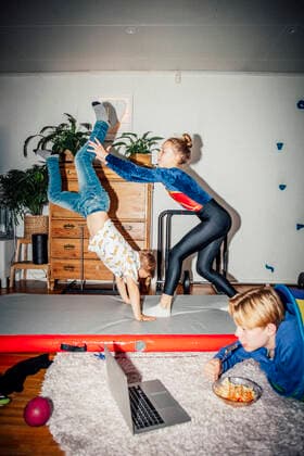 Male and female sibling practicing handstand while brother looking at laptop in living room Sweden, Stockholm, model released, property released Copyright: xMaskotx , MA81053