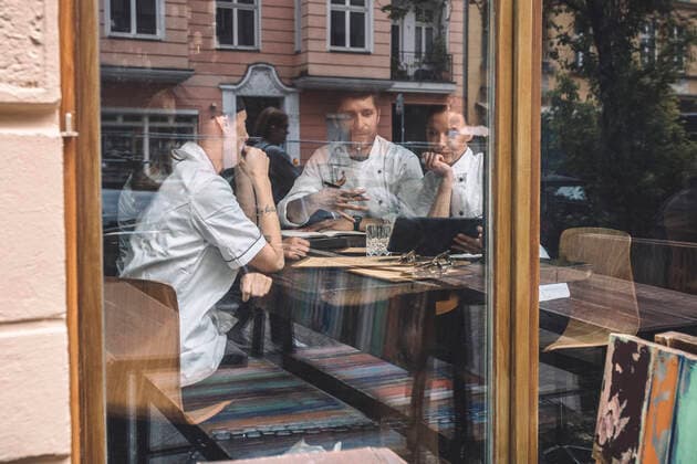 Male and female chefs discussing at restaurant table seen through glass window Germany, Berlin, model released, property released Copyright: xMaskotx , MA81399