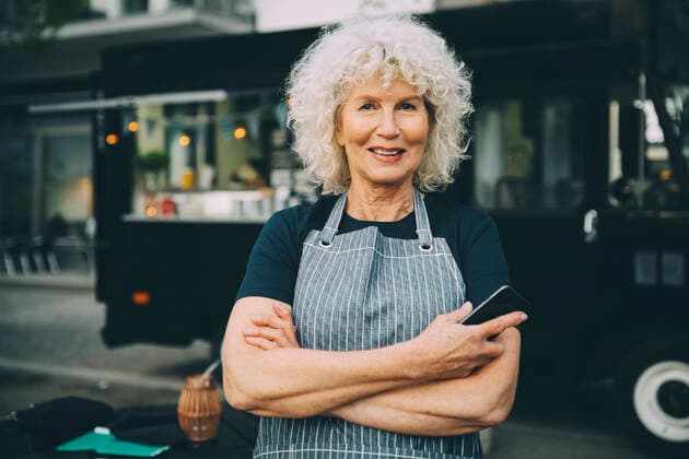 Portrait of senior owner with smart phone standing against food truck in city Sweden, Stockholm, model released, property released Copyright: xMaskotx , MA81560
