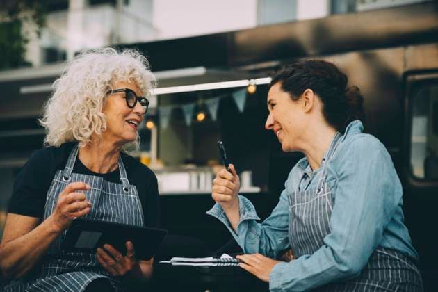 Internationaler Tag der Freundschaft IMAGO Creative: Internationaler Frauenmonat, Gesundheit, Frauen in der Menopause Senior owner talking to assistant against food truck in city Sweden, Stockholm, model released, property released Copyright: xMaskotx , MA81563