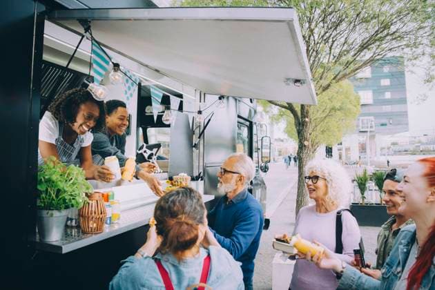 IMAGO Creative, Urban Lifestyle Smiling male and female customers talking to food truck owners in city Sweden, Stockholm, model released, property released Copyright: xMaskotx , MA81581