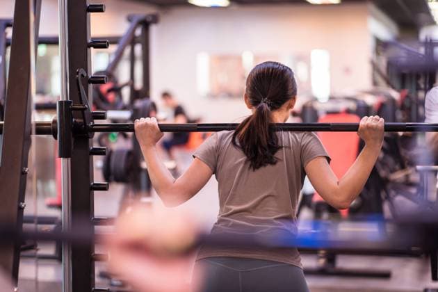 IMAGO Creative, Lifestyle, Tik Tok-Trend thatgirl Back view of unrecognizable sportswoman in active wear squatting with barbell in smith machine during intense workout looking away in modern gym Copyright: xJuanxAlbertoxRuizx Model Released