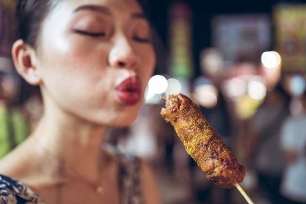 Asian female standing in Zhubei Night Market and cooling hot sausage on stick Copyright: xJuanxAlbertoxRuizx Model Released