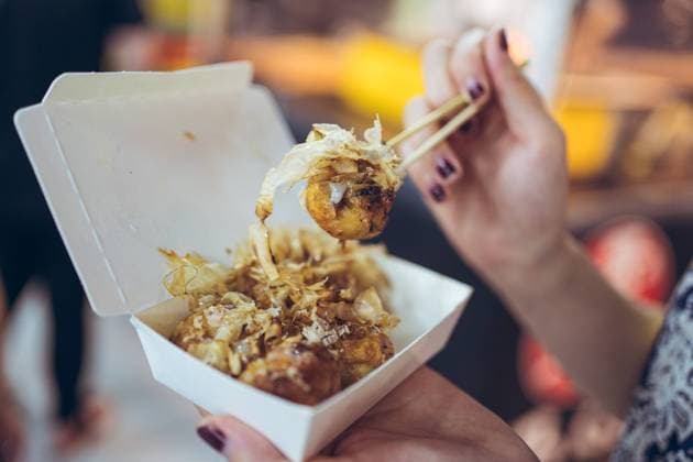 Crop unrecognizable female standing in Zhubei Night Market and eating delicious Takoyaki octopus balls Copyright: xJuanxAlbertoxRuizx Model Released