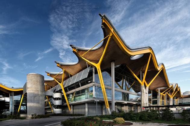 Unusual facade of Madrid Barajas airport with wavy roof and vivid yellow pillars in composition with window walls under blue sky in Spain Copyright: xKavixSanchezx Model Released