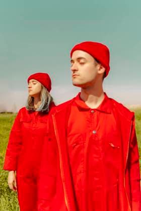 Young couple wearing red overalls and hats standing in nature with eyes closed model released Symbolfoto ERRF03337