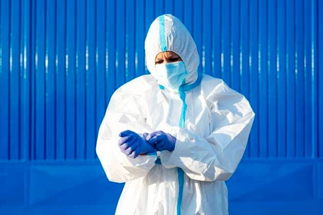 Female nurse wearing glove while standing against blue wall on sunny day model released Symbolfoto PGF00118