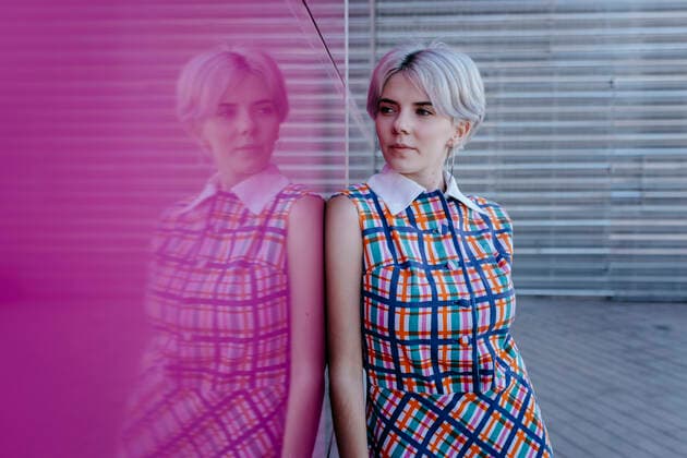 Thoughtful young woman with short hair standing by pink glass wall model released Symbolfoto TCEF00775