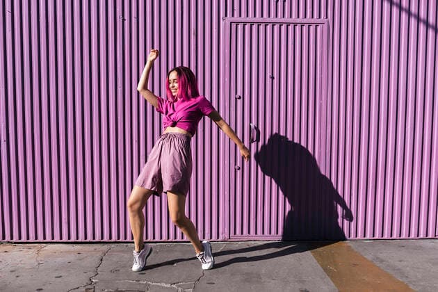 Young woman with dyed red hair dancing in front of purple wall in the city model released Symbolfoto TCEF00994