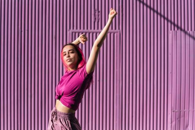 Young woman with dyed red hair dancing in front of purple wall in the city model released Symbolfoto TCEF00999