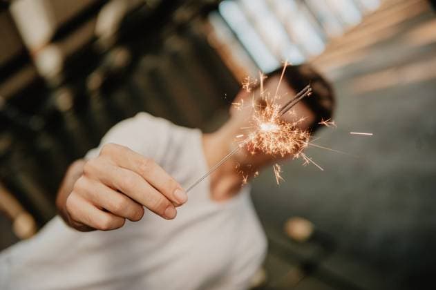 Young handsome man in white T-shirt standing inside building and holding burning Bengal light in hand, Model released Copyright: xLuciaxVargasx MR