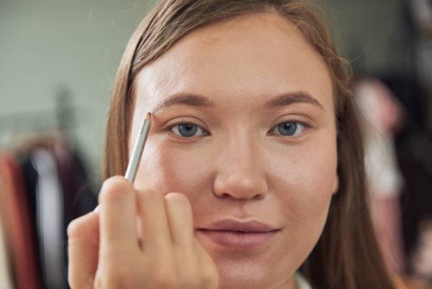 IMAGO Creative: Kreative Renaissance -- der junge Entrepreneur Crop focused makeup artist doing eyebrows on young beautiful female client looking at camera while working in contemporary studio Copyright: xLuisxGomezx Model Released