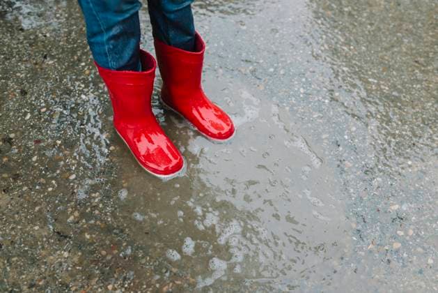 IMAGO Creative: Klimawandel - Umwelterziehung Adorable joyful child in red raincoat and rubber boots having fun jumping in puddle on street in park in gray day, Model released Copyright: xMartaxMachinx MR