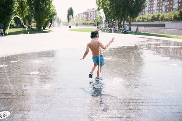 IMAGO Creative: Sommer, Sommertage im Stadtpark Back view of anonymous little boy in swimsuits standing near jet of water splashing out of fountain on street, Model released Copyright: xMartaxMachinx MR