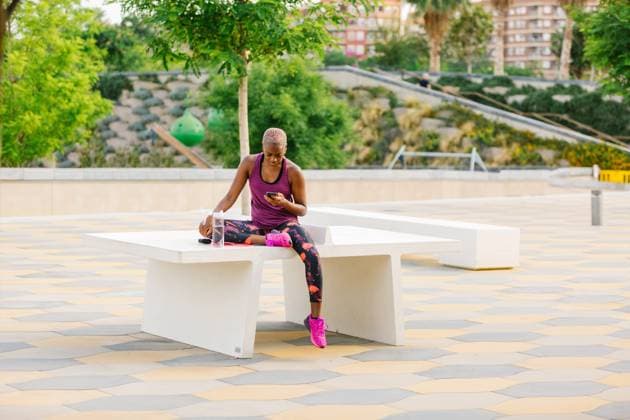 IMAGO Creative: St?dte im Wandel Black sportswoman browsing smartphone after workout, Model released Copyright: xMiguelxVallsx MR