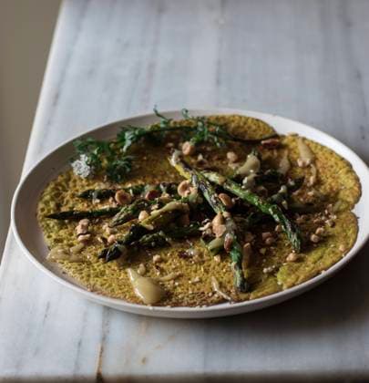 Top view of white plate with oat crepe with asparagus and tahini paste served on rustic board with greens Copyright: xOlgaxVilax Model Released