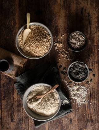 IMAGO Nature: Unsere Erde, Klimawandel, Ern?hrung, Pflanzen der Zukunft, Quinoa Top view of bowls with millet and quinoa for granola preparation placed on wooden table near napkins and seeds Copyright: xOlgaxVilax Model Released