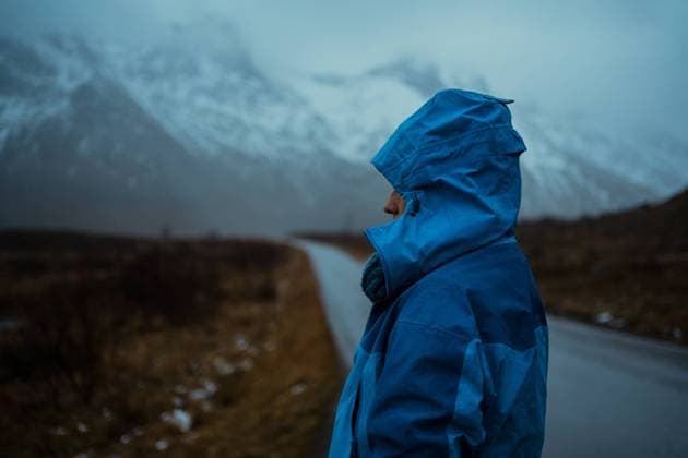 IMAGO Creative: Wintersport, Mode Back view of relaxed unrecognizable person in blue warm clothes and hoodie standing on asphalt road going to snowy foggy mountains in Lofoten Copyright: xRafaxCortesx Model Released
