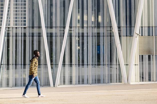 young black man passing in front of a modern office building, lifestyle concept, Model released Copyright: xRaulxMelladox MR