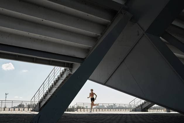 Side view of determined female athlete running fast during outdoor workout near stairways of stadium Copyright: xSergeyxMironovx Model Released