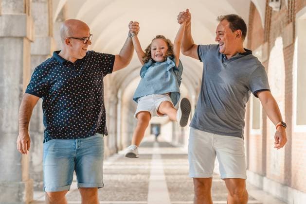 Cheerful fathers lifting cute girl above ground while walking along passage in city at weekend in summer, Model released Copyright: xSixAndxSix MR