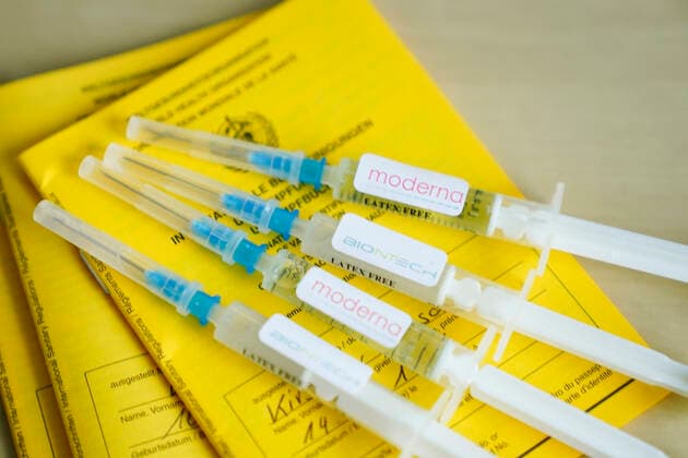 Symbolfoto Impfspritze Biontech und Impfpass Symbolfoto von Moderna und BIONTECH Impfspritze auf einem Impfpass. Beide Pharmaunternehmen haben aktuell zugelassene Impfstoffe gegeen das Corona Virus Deutschland