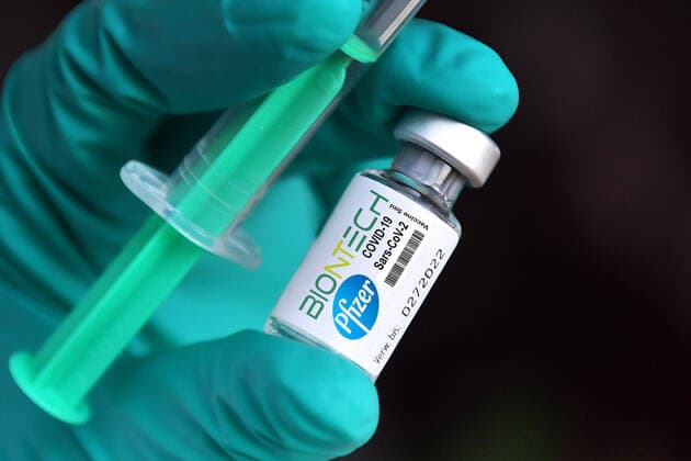 FOTOMONTAGE-Themenbild,Symbolfoto:Impfstoff von Biontech Pfizer vor Zulassung in Deutschland. Medizinisches Personal haelt eine Impfspritze und eine Impfdose mit Impfstoff gegen das Coronavirus. Impfung mit Einwegspritze und Impfstoff zur Injektion mit einer Kanuele. Haende in Schutzhandschuhen.