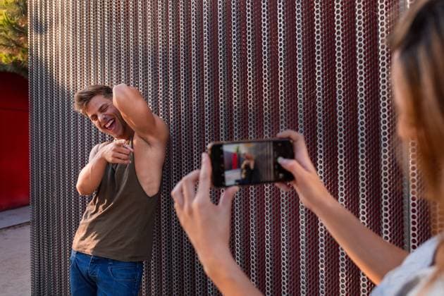 Attractive young man and woman smiling and posing while standing near wall on street Copyright: xWidetapex Model Released