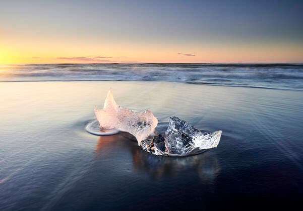 Creative Highlights World Glowing ice piece on wet shore Höfn, Iceland CR_OSBJ201216-587898-01