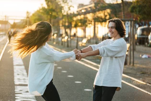 Side view happy guy holding hands of lady with windy hairs and whirling on asphalt walkway in sunny day on blurred background Copyright: xAlexandraxCoelhox Model Released