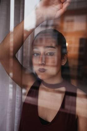 young woman dressed in red is behind a window with the reflection of the buildings of the city Copyright: xGuadalupexRodriguezx Model Released