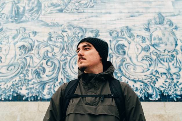 Head of man in warm clothes standing at white wall decorated with blue ornament., Model released Copyright: xJanoxMadrizx MR