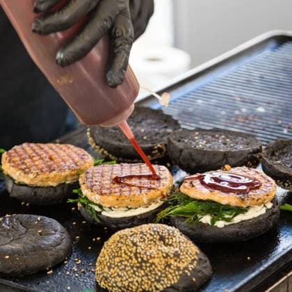Beef burgers ready to serve on food stall. Chef making beef burgers outdoor on open kitchen international food festival event. Street food ready to serve on a food stall.burger, food, stall, hamburger, street, street food, beef, bun, fast, meat, snack, outdoors, cuisine, seller, vendor, catering, lunch, meal, delicious, restaurant, junk food, sauce, salad, outdoor, urban, event, making, chef, desk, decorate, tomatoes, sandwich, to go, take out, cart, grill, plate, dressing, ketchup, mayonnaise, lettuce, gloves, black, wholemeal, healthy, city, open kitchen, 