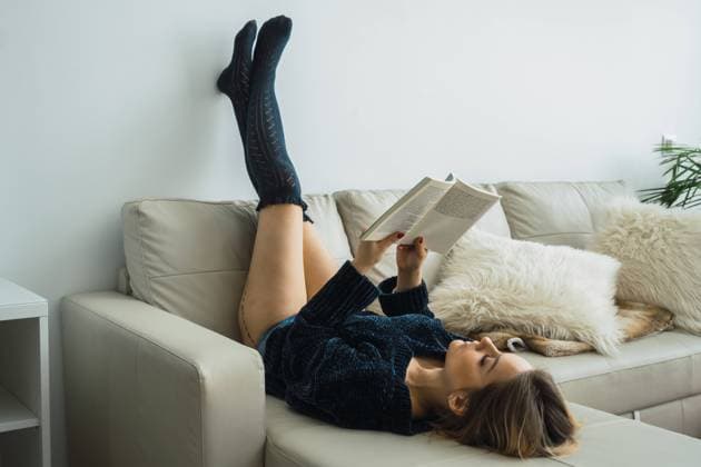 IMAGO Creative: Gesundheit, Stille Casual girl in sweater and stockings lying on couch enjoying book and reading alone in silence., Model released Copyright: xKikexArnaizx MR