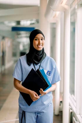 Portrait of smiling female nurse with file standing in hospital corridor Sweden, Stockholm, model released, property released Copyright: xMaskotx , MA83332