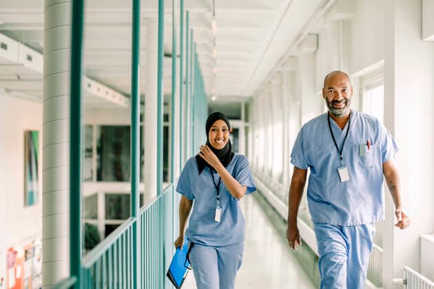 Portrait of coworkers talking while walking in corridor at hospital Sweden, Stockholm, model released, property released Copyright: xMaskotx , MA83336