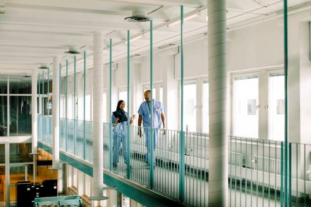 Male and female colleagues talking while walking in corridor at hospital Sweden, Stockholm, model released, property released Copyright: xMaskotx , MA83337
