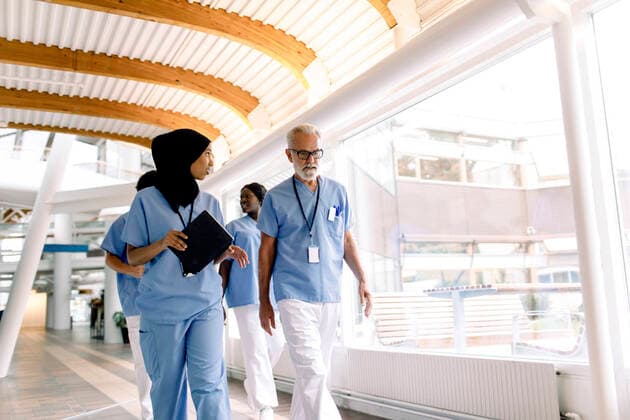 IMAGO Creative: Kollidierende Kulturen Confident male and female nurses talking while walking in hospital corridor Sweden, Stockholm, model released, property released Copyright: xMaskotx , MA83356