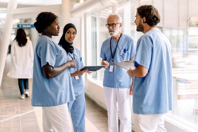 Confident male and female nurses talking in hospital corridor Sweden, Stockholm, model released, property released Copyright: xMaskotx , MA83360