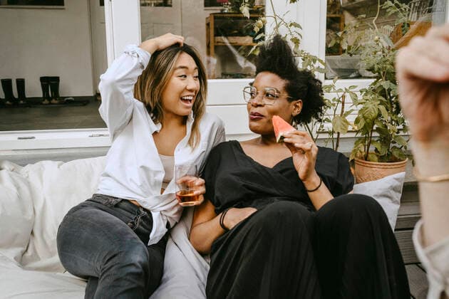 Happy woman with drinking glass talking to female friend while sitting in backyard Sweden, Stockholm, model released, property released Copyright: xMaskotx , MA83449