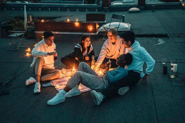 IMAGO Creative: Jahreszeit Frühling, Picknick High angle view of male and female friends talking on building terrace during sunset Germany, Berlin, model released, property released Copyright: xMaskotx , MA83578
