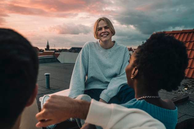IMAGO Creative, Jahreszeit Herbst, Ferien IMAGO Creative: Urban Diversity Portrait of smiling female sitting with friends on building terrace during sunset Germany, Berlin, model released, property released Copyright: xMaskotx , MA83596