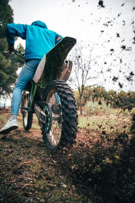 IMAGO Creative, Jahreszeit Herbst, Ferien Male teenage rider spinning motorcycle tire while blowing dirt in forest during autumn model released Symbolfoto ACPF00904
