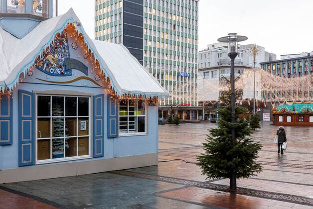 Essen, Ruhrgebiet, Nordrhein-Westfalen, Deutschland - Essener Innenstadt in Zeiten der Coronakrise beim zweiten Lockdown am Tag vor Heiligabend, die Geschäfte und die wenigen Weihnachtsmarktbuden sind geschlossen, eine Seniorin geht mit ihren Einkäufen über den leeren Kennedyplatz. Essen Nordrhein-Westfalen Deutschland