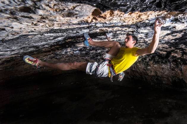 Young male sportsperson climbing rock with determination in cave model released Symbolfoto GGGF00443