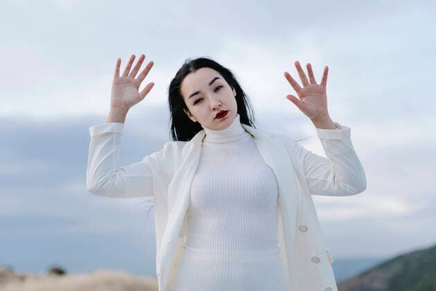 Woman with hand raised standing against sky model released Symbolfoto TCEF01411