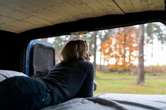 IMAGO Creative: Herbst, Touren mit dem Camper Comfortable woman looking outside while lying on bed in camper van model released Symbolfoto  WPEF03814