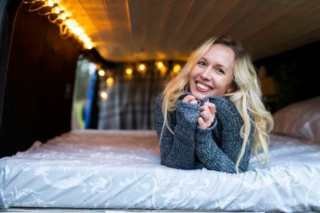 IMAGO Creative: Herbst, Touren mit dem Camper Smiling woman lying on bed in camper van model released Symbolfoto  WPEF03816