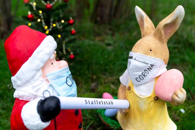 Symbolfoto Staffeluebergabe von Weihnachtsmann und Osterhase zum Corona Lockdown und Schutzmassnahmen Aktuell, Sybolbild Weihnachtsmann und Osterhase mit Maske. Der Weihnachtsmann uebergibt symbolisch den Staffelstab an den Osterhasen. Werden die Corona Schutzmassnahmen oder der Lockdown verlaengert bis Ostern. Deutschland
